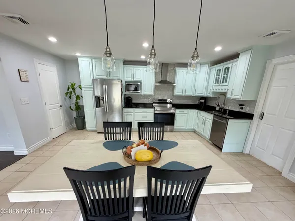 a kitchen with stainless steel appliances granite countertop a refrigerator a stove a sink a dining table and chairs
