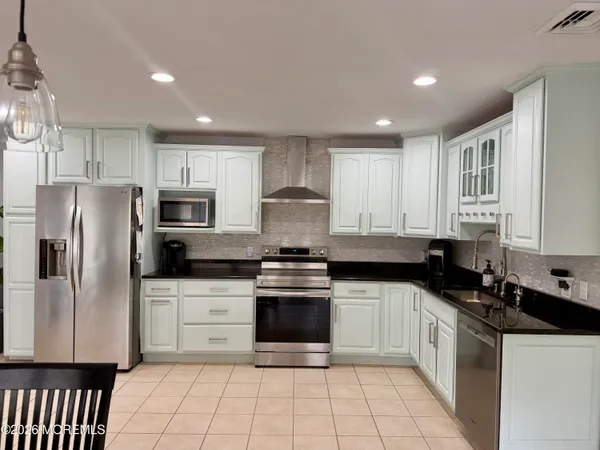 a kitchen with stainless steel appliances granite countertop a stove a sink and a refrigerator