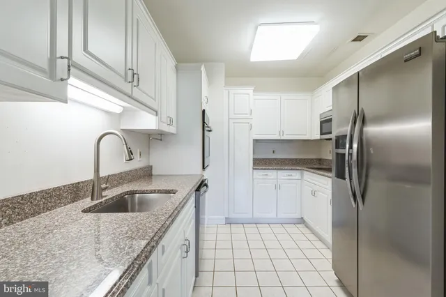 a kitchen with granite countertop white cabinets and stainless steel appliances