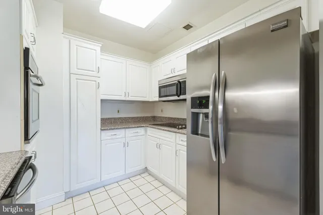 a kitchen with granite countertop white cabinets stainless steel appliances and a sink