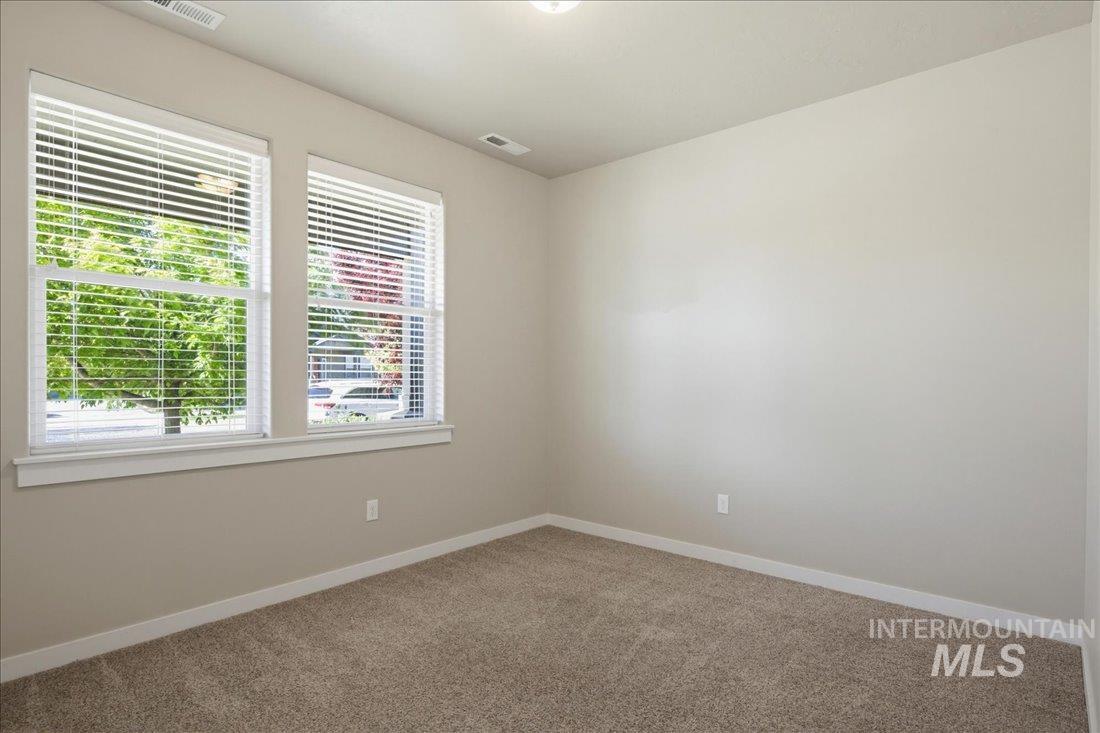 12460 West Azure Street Boise, ID 83713 - Photo 24 of 34 Room featuring two windows with horizontal blinds, neutral wall paint, and light brown carpeting
