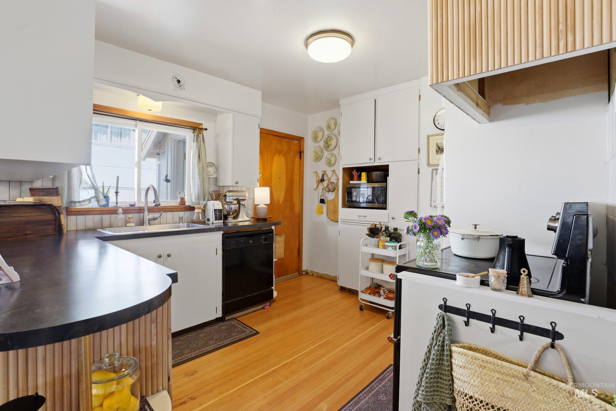 725 Elm Street Potlatch, ID 83855 - Photo 18 of 50 Kitchen featuring white cabinets, dishwasher, dark countertops, and light wood finished floors