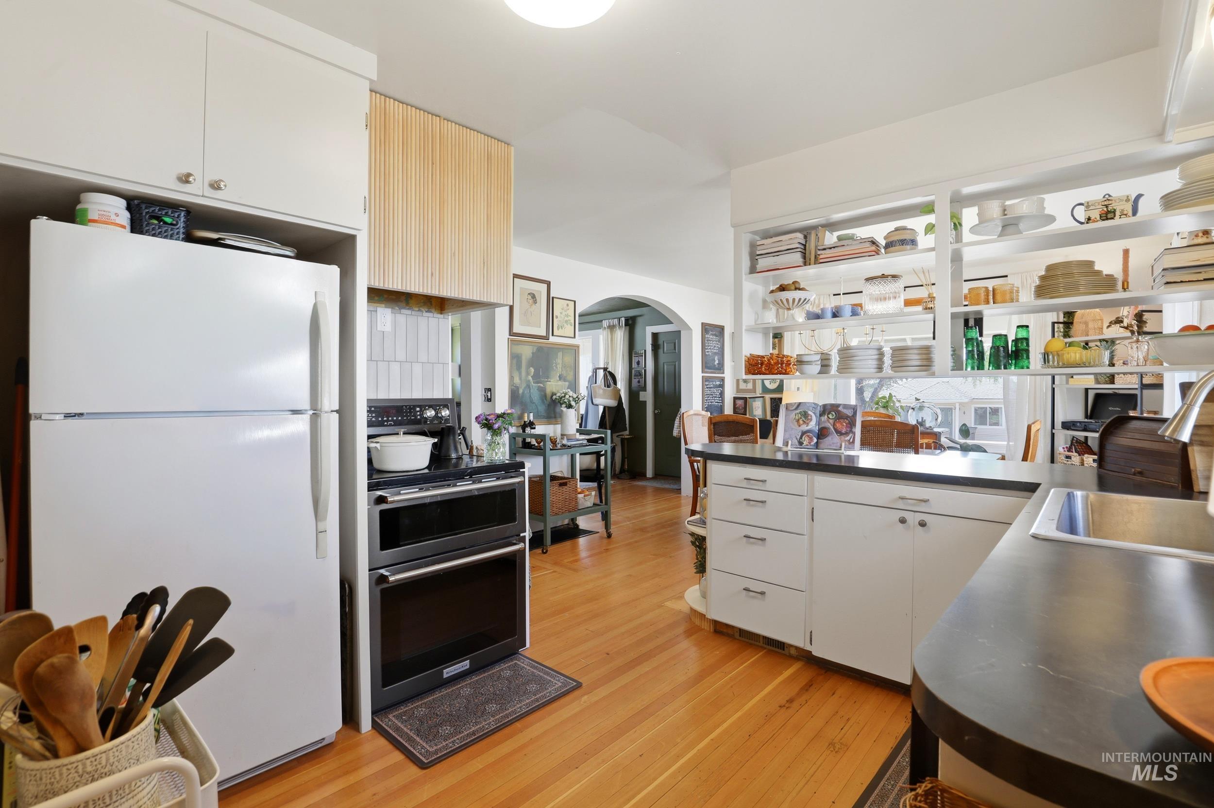 725 Elm Street Potlatch, ID 83855 - Photo 19 of 50 Kitchen featuring freestanding refrigerator, dark countertops, arched walkways, and white cabinetry