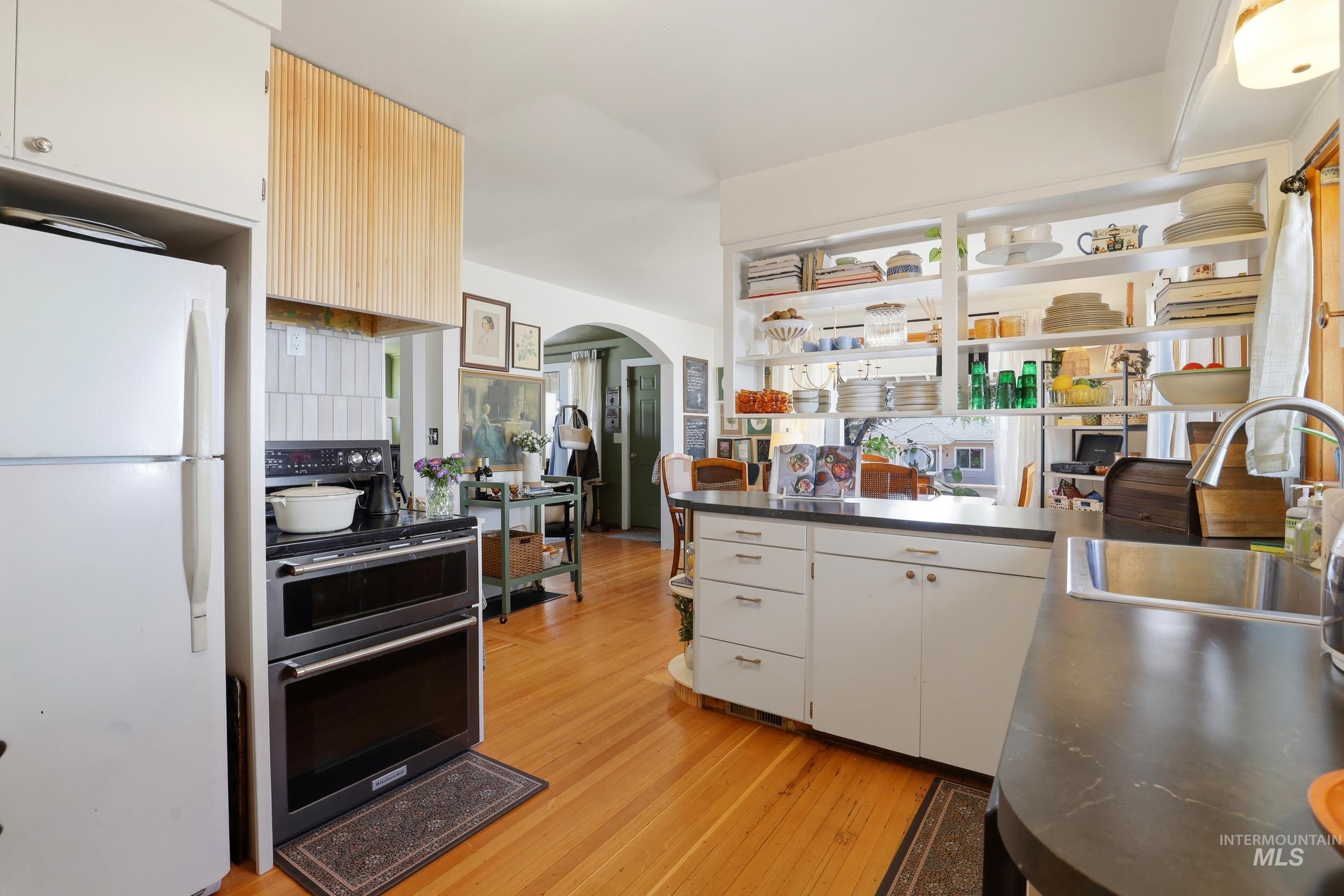 725 Elm Street Potlatch, ID 83855 - Photo 21 of 50 Kitchen featuring freestanding refrigerator, arched walkways, double oven range, light wood-style flooring, and open shelves
