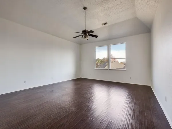 an empty room with wooden floor chandelier and windows