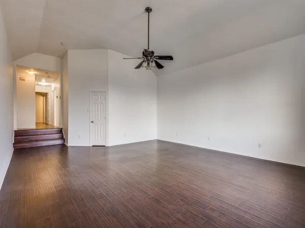 an empty room with wooden floor ceiling fan and windows