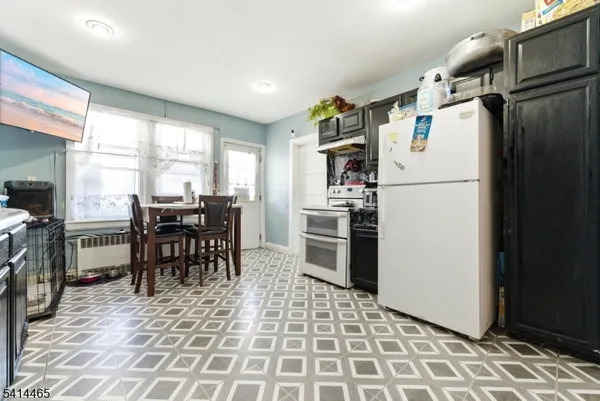 a kitchen with stainless steel appliances a refrigerator a stove a dining table and chairs with wooden floor