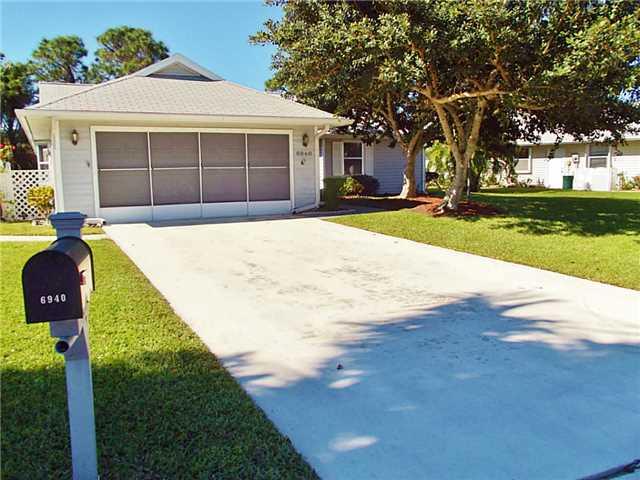 6940 Southeast Lillian Court Stuart, FL 34997 - Photo 2 of 25 a front view of a house with a yard and garage