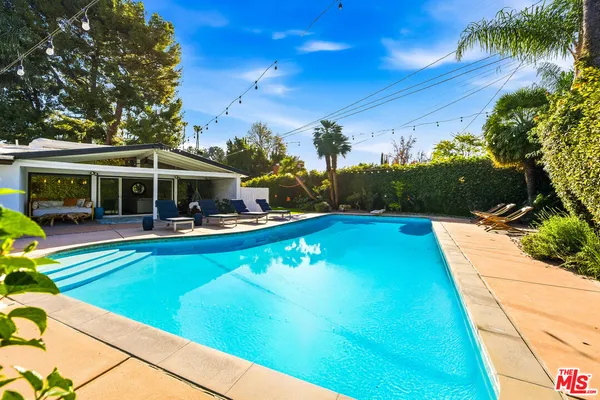 a view of swimming pool with lawn chairs under an umbrella