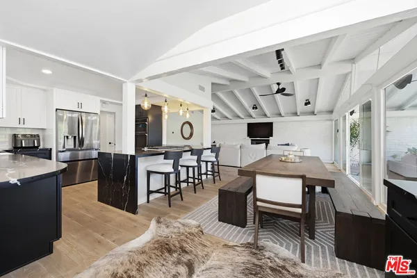 a living room with stainless steel appliances kitchen island granite countertop furniture a rug kitchen view and a chandelier