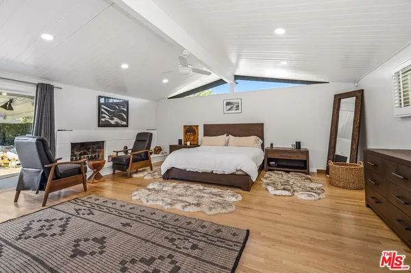 a bedroom with a bed a desk and chair with wooden floor