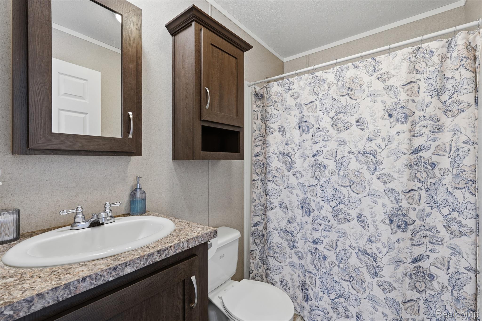 92 Normandy Drive Howell, MI 48843 - Photo 16 of 24 Bathroom featuring a vanity with an integrated sink, dark wood-finish cabinetry, a framed wall mirror, and a full shower with a patterned curtain