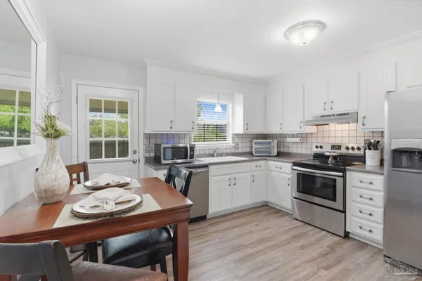 a kitchen with stainless steel appliances kitchen island granite countertop a stove a sink a refrigerator dining table and chairs