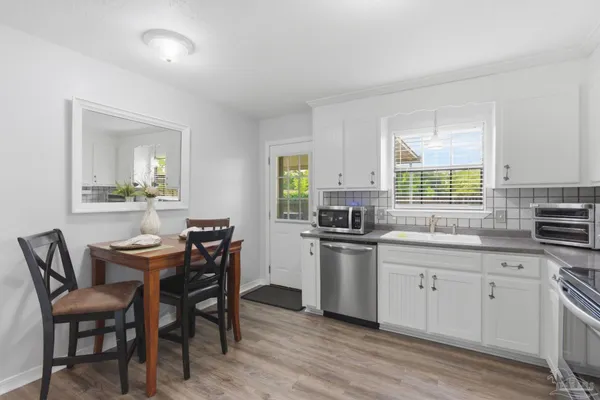 a kitchen with stainless steel appliances a table chairs sink refrigerator and cabinets