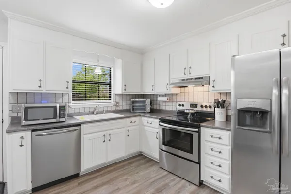 a kitchen with white cabinets and stainless steel appliances