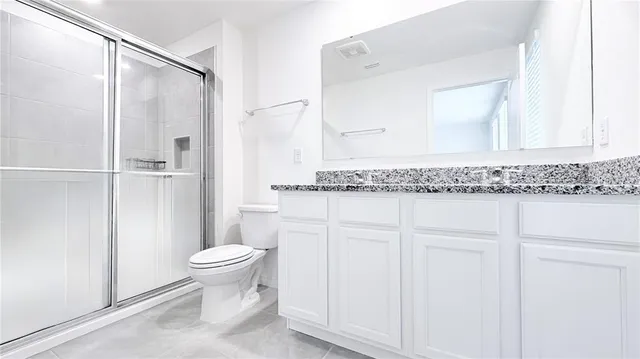 a bathroom with a granite countertop sink and a toilet
