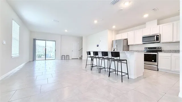 a large white kitchen with kitchen island a large window a sink and a counter space