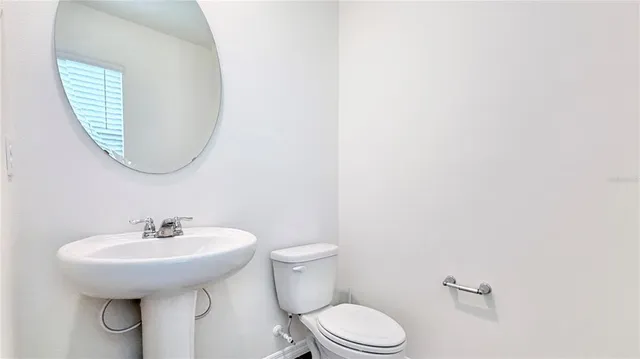 a bathroom with a toilet a sink and mirror