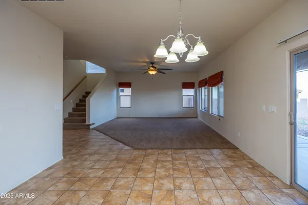 a view of a livingroom with a chandelier fan and kitchen view