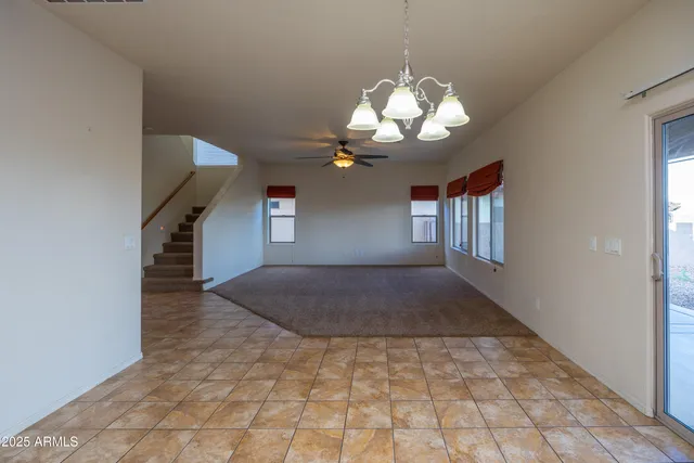 a view of a livingroom with a chandelier fan and kitchen view