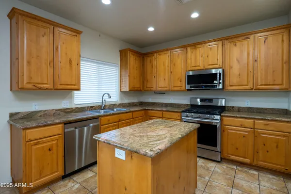a kitchen with stainless steel appliances granite countertop wooden cabinets a stove a sink and a microwave