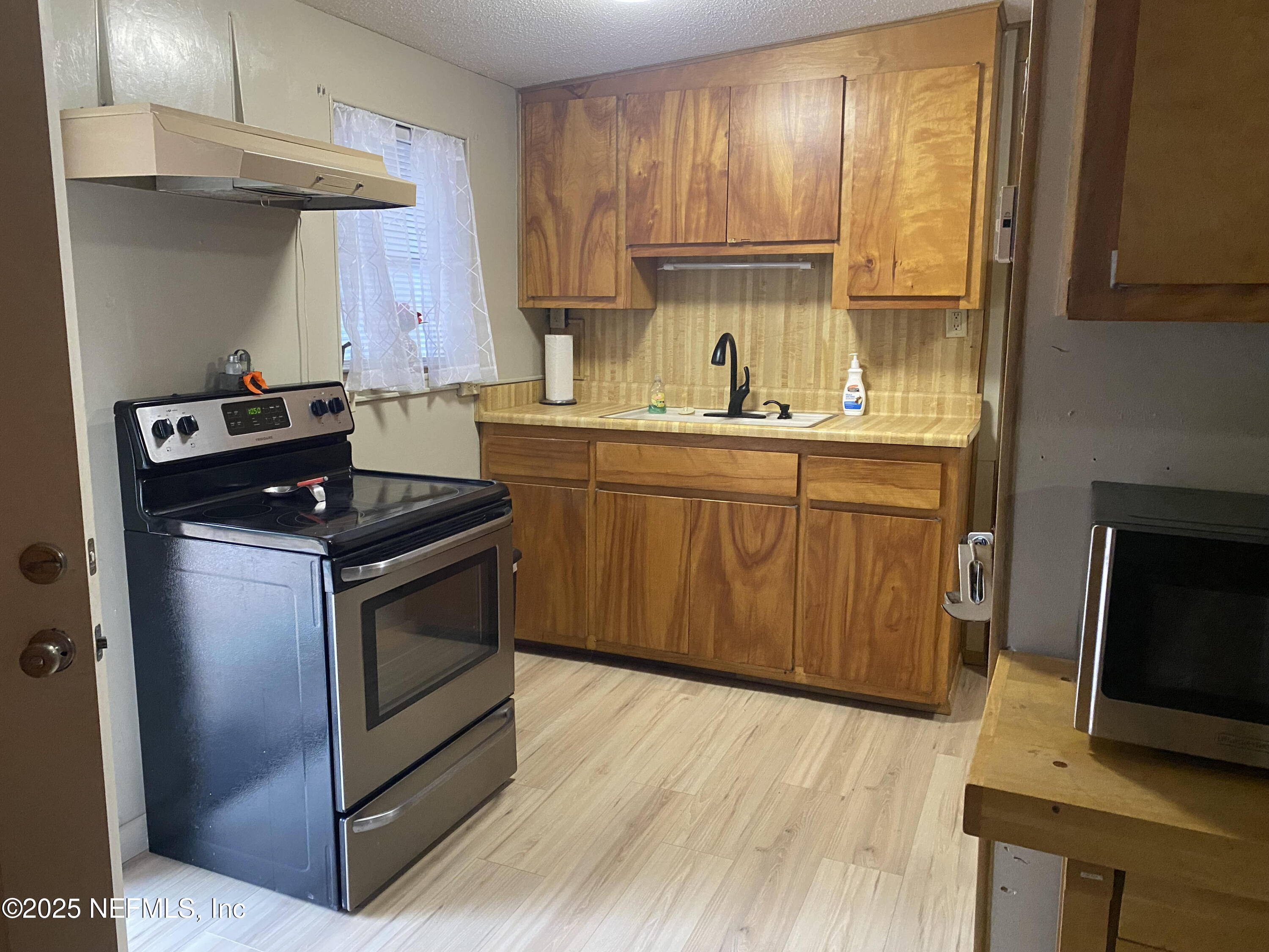 8093 Breezy Point Road East Keystone Heights, FL 32656 - Photo 11 of 35 a kitchen with stainless steel appliances granite countertop a stove a sink and a microwave