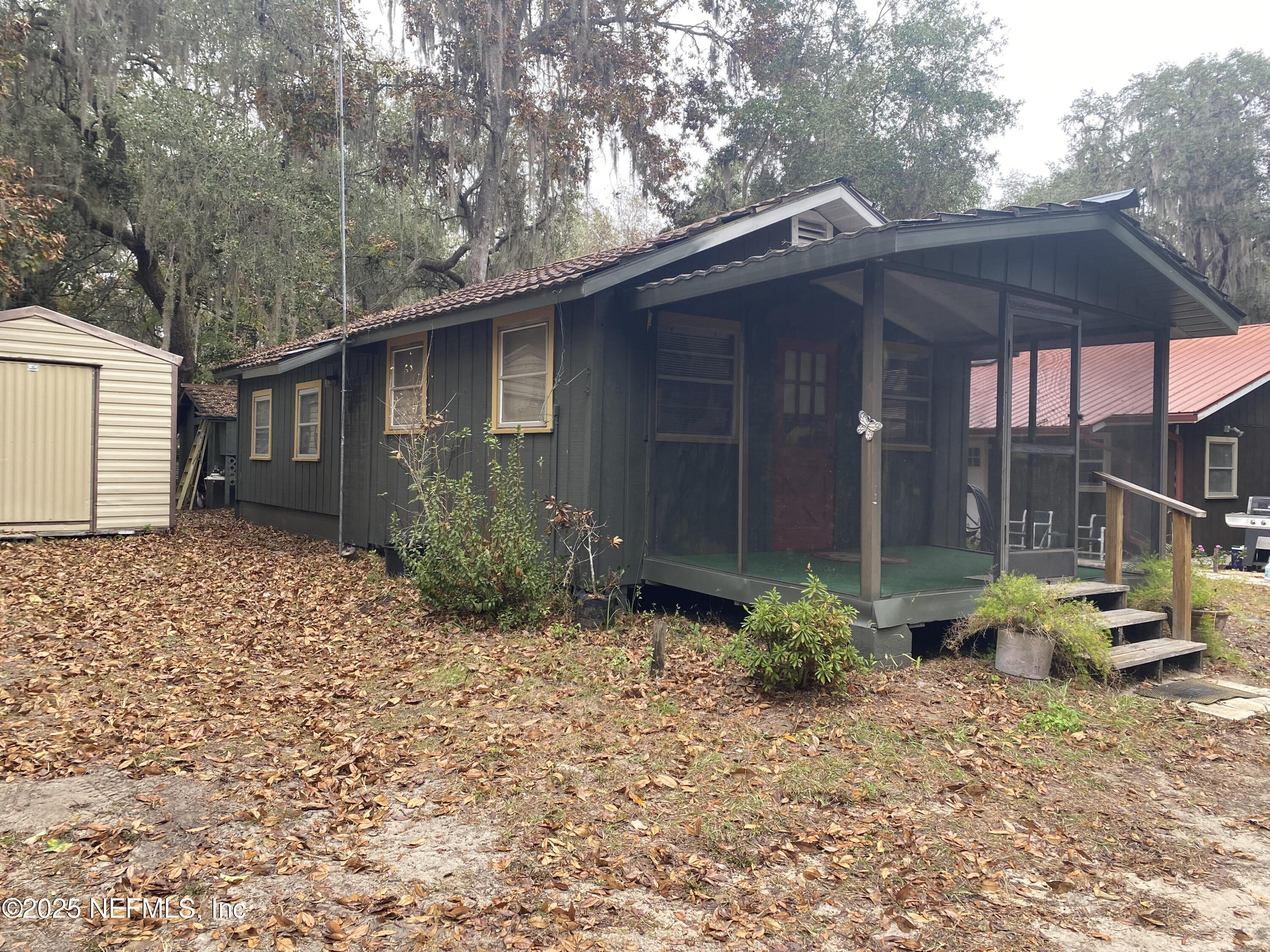 8093 Breezy Point Road East Keystone Heights, FL 32656 - Photo 27 of 35 a backyard of a house with potted plants and large tree