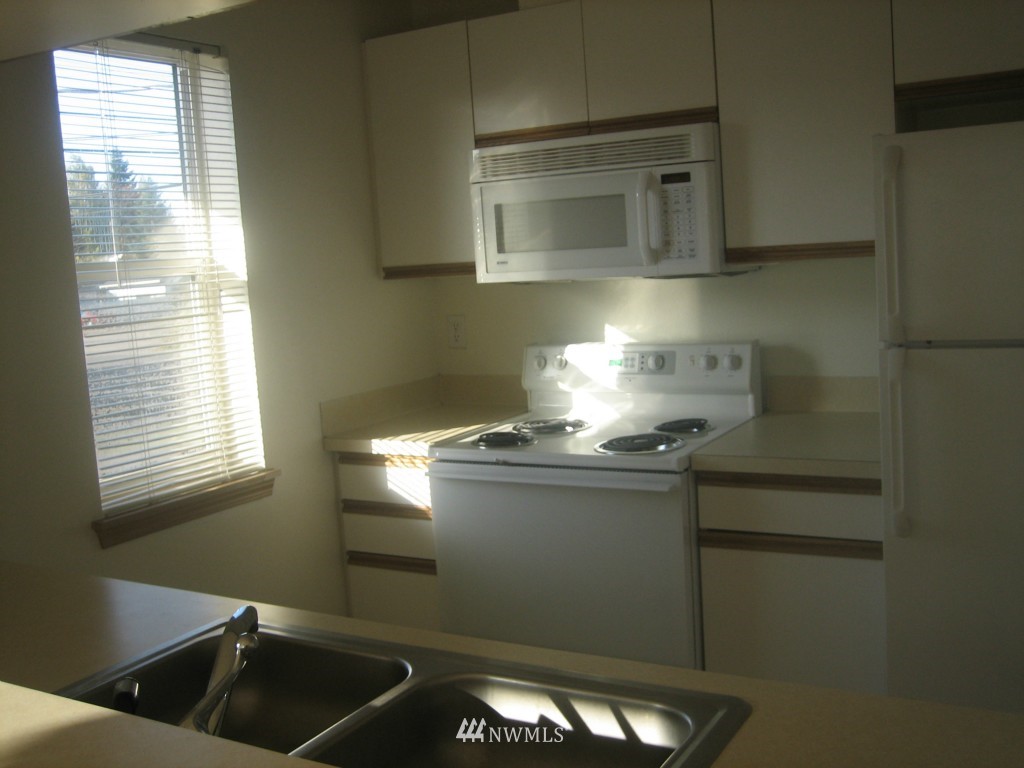 703 North 95th Street Seattle, WA 98103 - Photo 7 of 11 a kitchen with stainless steel appliances granite countertop a sink and a stove