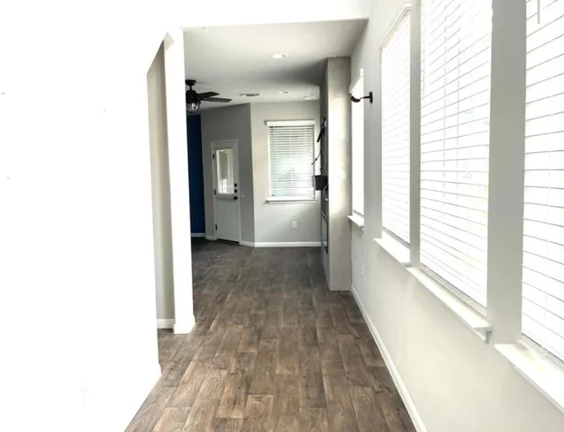a view of a hallway with wooden floor and windows