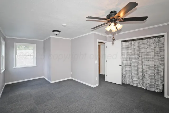 an empty room with windows and ceiling fan