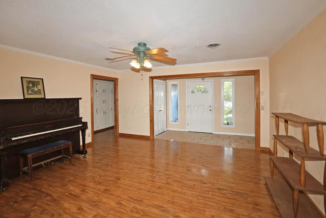 a view of an empty room with a window and wooden floor