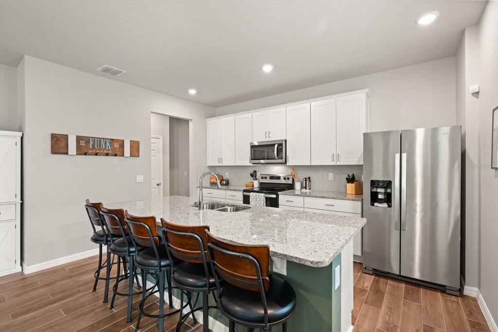 140 South Zuni Road St. Cloud, FL 34771 - Photo 11 of 35 a kitchen with stainless steel appliances granite countertop a dining table chairs refrigerator and cabinets