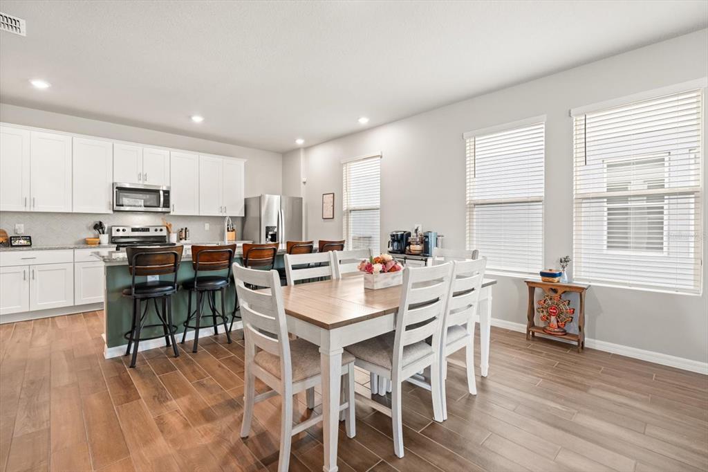 140 South Zuni Road St. Cloud, FL 34771 - Photo 8 of 35 a kitchen with a dining table chairs wooden floor cabinets and stainless steel appliances