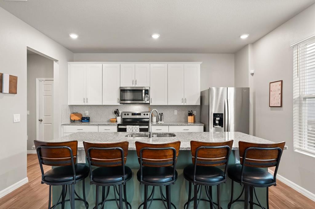 140 South Zuni Road St. Cloud, FL 34771 - Photo 10 of 35 a kitchen with stainless steel appliances kitchen island granite countertop a dining table and chairs