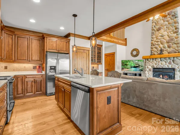 a kitchen with stainless steel appliances granite countertop a stove a refrigerator a kitchen island a sink dishwasher a dining table and chairs with wooden floor