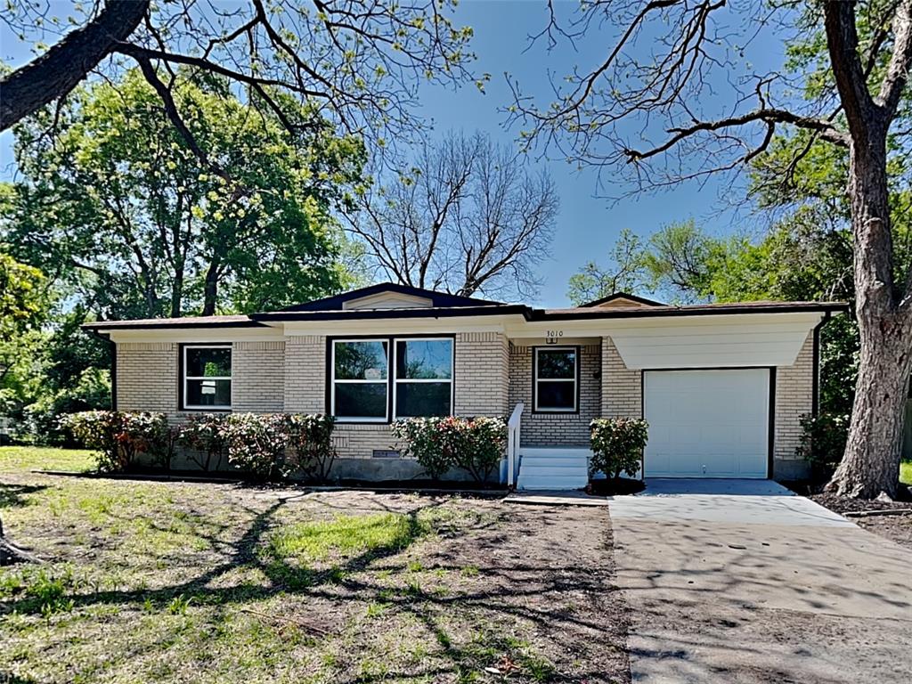 View of front of property with brick siding, an attached garage, and driveway