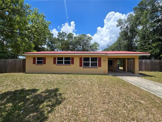 a front view of house with yard and trees in the background