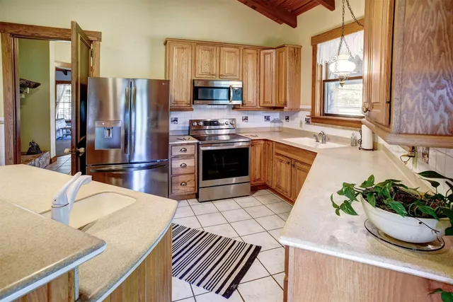 a kitchen with stainless steel appliances a sink a microwave a refrigerator and cabinets