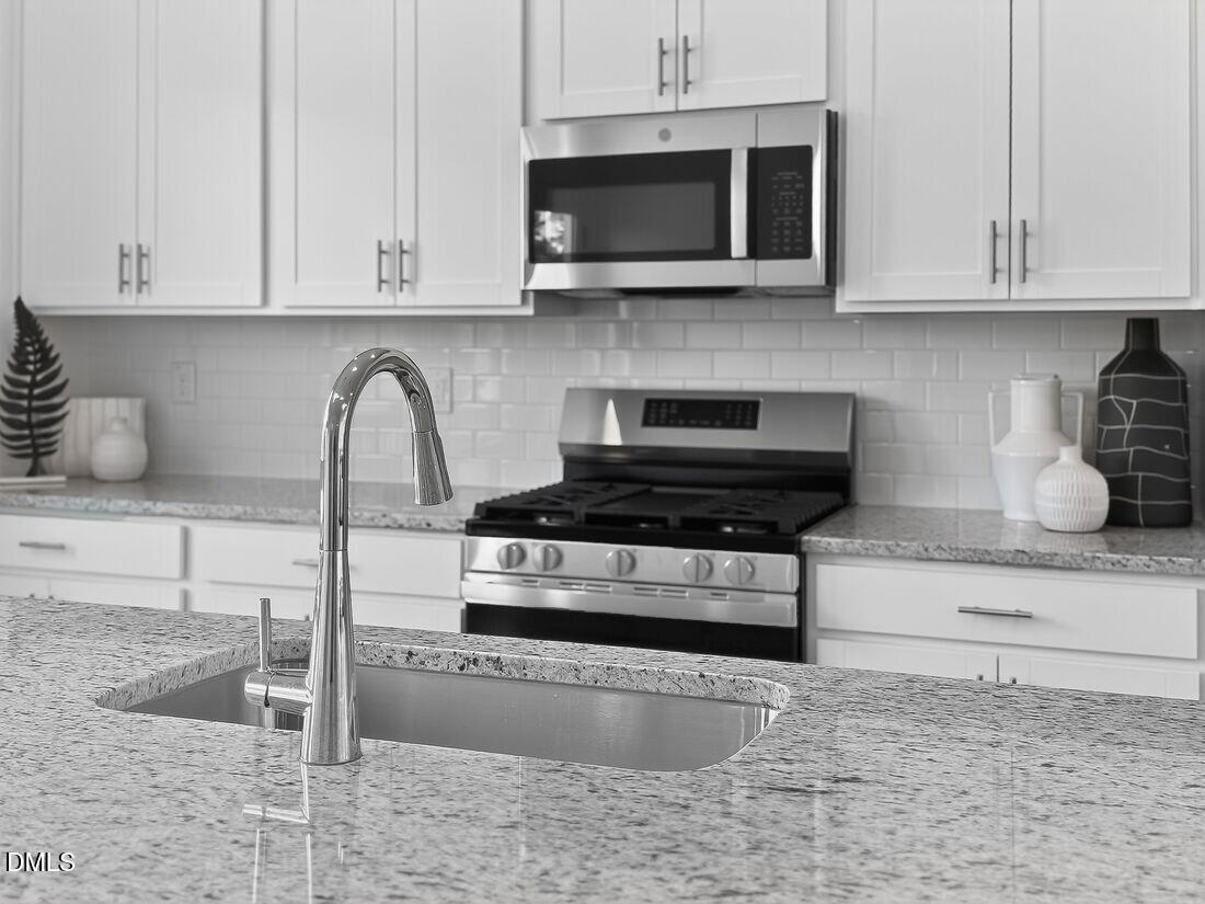 1324 West Garner Road, Unit 101 Garner, NC 27529 - Photo 11 of 29 a kitchen with granite countertop a stove a microwave and cabinets