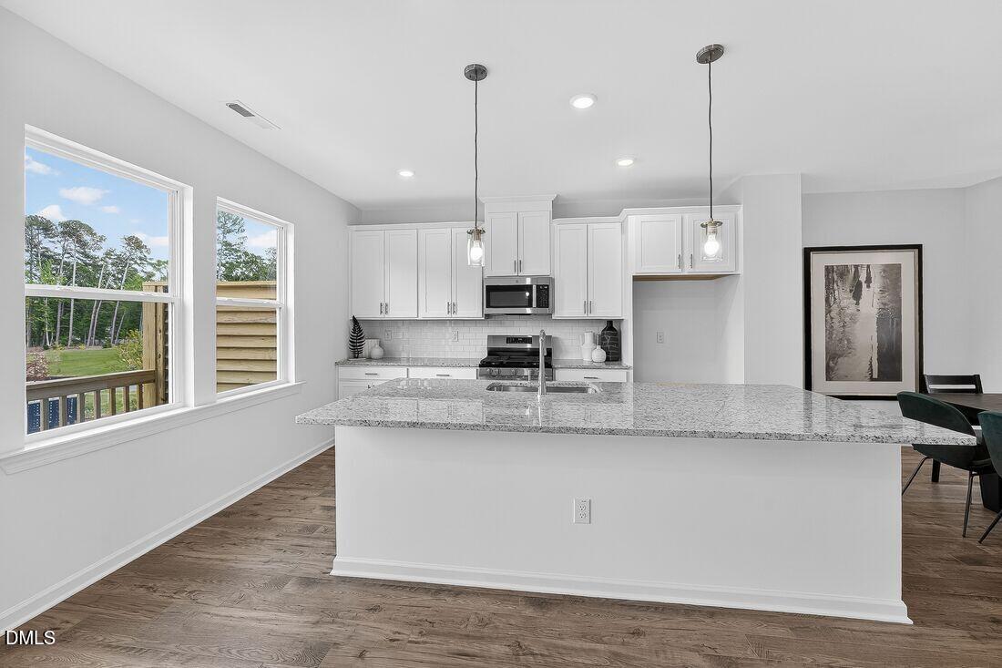 1324 West Garner Road, Unit 101 Garner, NC 27529 - Photo 13 of 29 a large kitchen with granite countertop a stove a sink a center island and stainless steel appliances