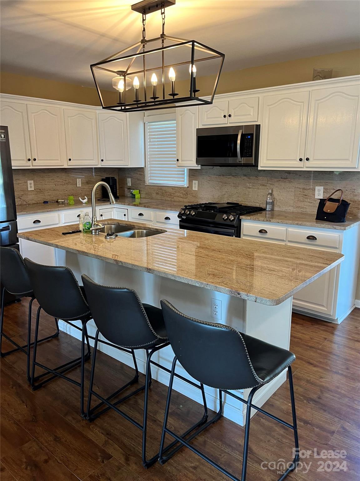 105 Doe Ridge Drive Cleveland, NC 27013 - Photo 2 of 4 a kitchen with stainless steel appliances granite countertop a sink a stove a microwave and wooden cabinets
