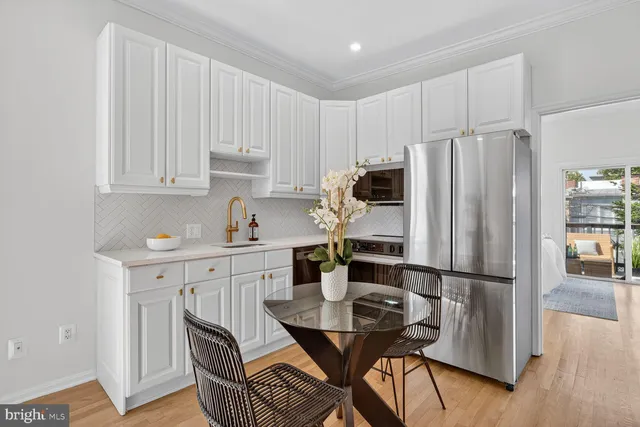 a kitchen with stainless steel appliances granite countertop a refrigerator a sink dishwasher a stove and white cabinets with wooden floor