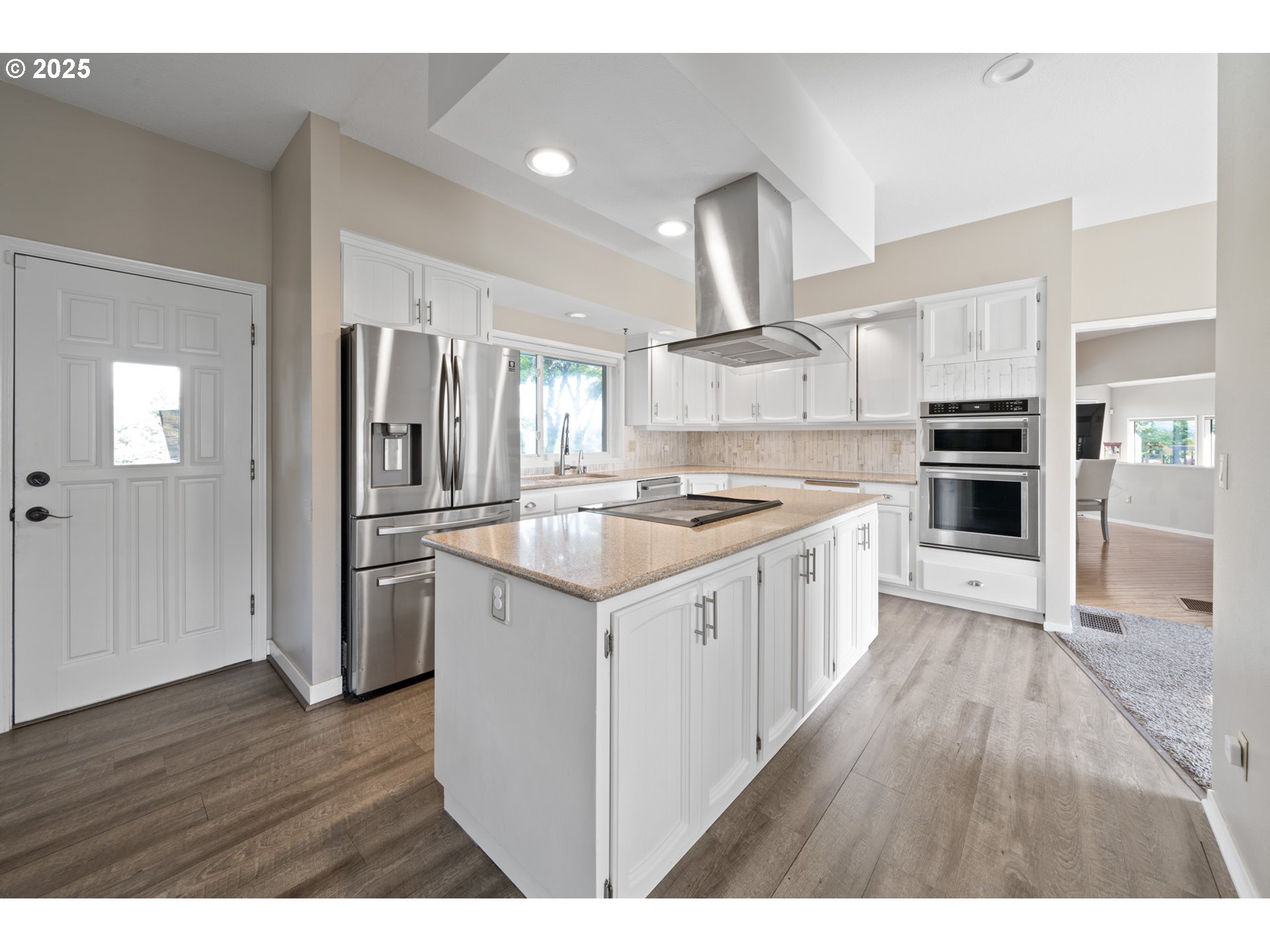 14330 Southeast Donatello Loop Happy Valley, OR 97086 - Photo 7 of 45 a kitchen with stainless steel appliances kitchen island wooden floors and white cabinets