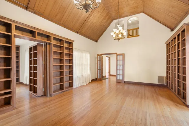 a view of an empty room with wooden floor and windows
