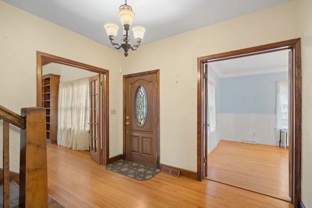 a view of an empty room with wooden floor fireplace and a window