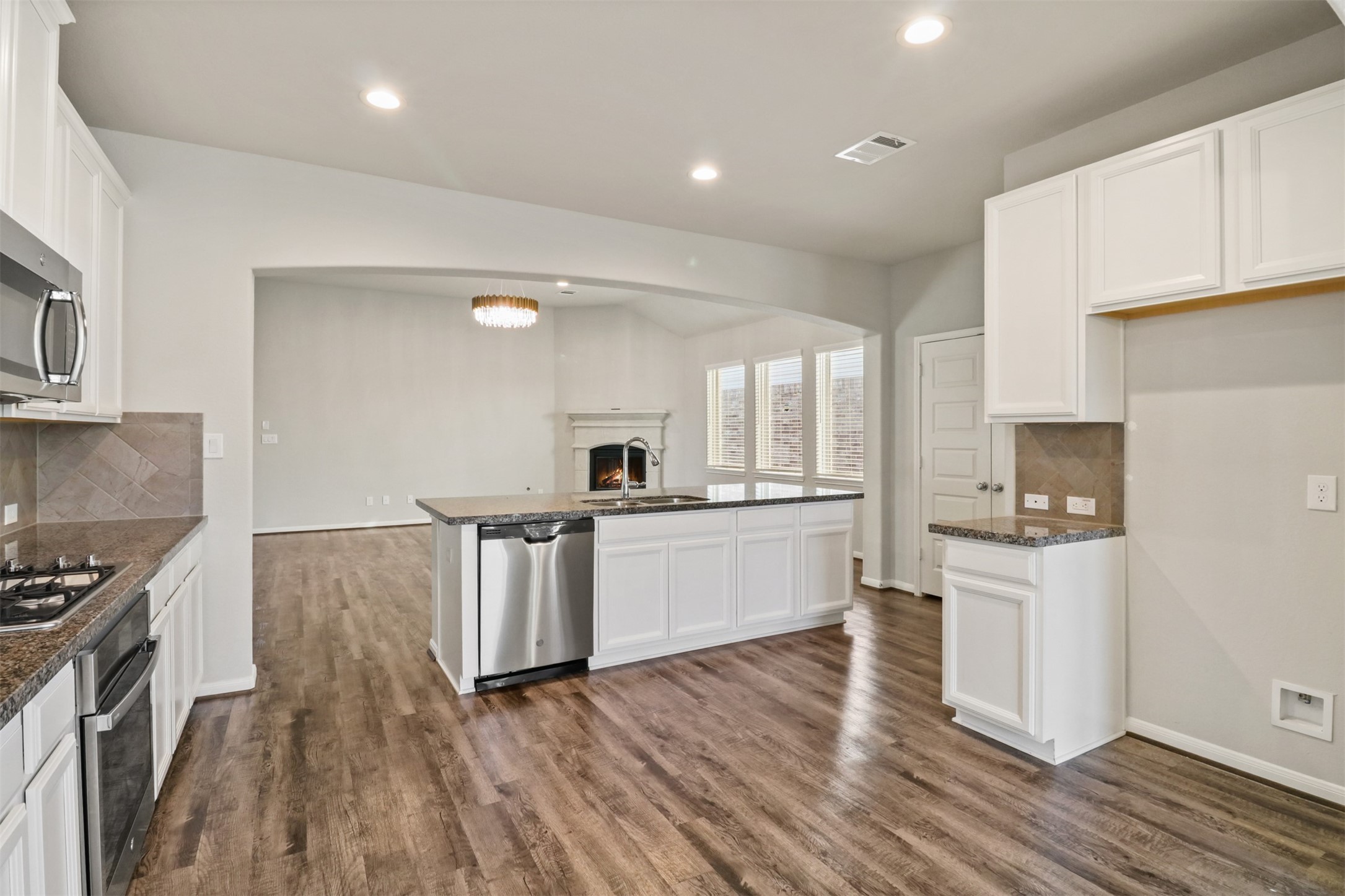 6010 Mapleton Meadow Lane Richmond, TX 77407 - Photo 8 of 34 a kitchen with stainless steel appliances a stove top oven a sink a refrigerator white cabinets and wooden floor