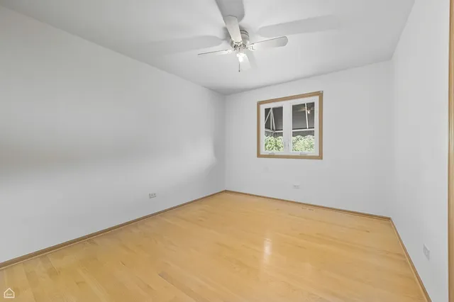 an empty room with windows and ceiling fan