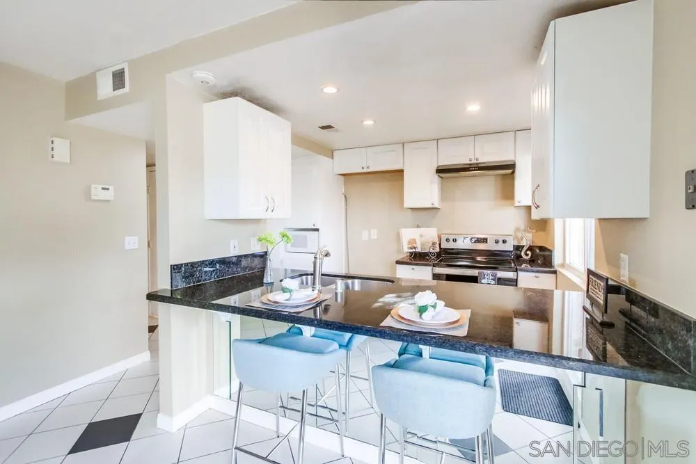 933 Greenfield Drive, Unit D El Cajon, CA 92021 - Photo 6 of 41 a kitchen with a stove a sink a kitchen island with chairs and white cabinets