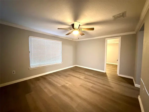 a view of an empty room with window and wooden floor