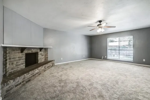 an empty room with windows and fireplace